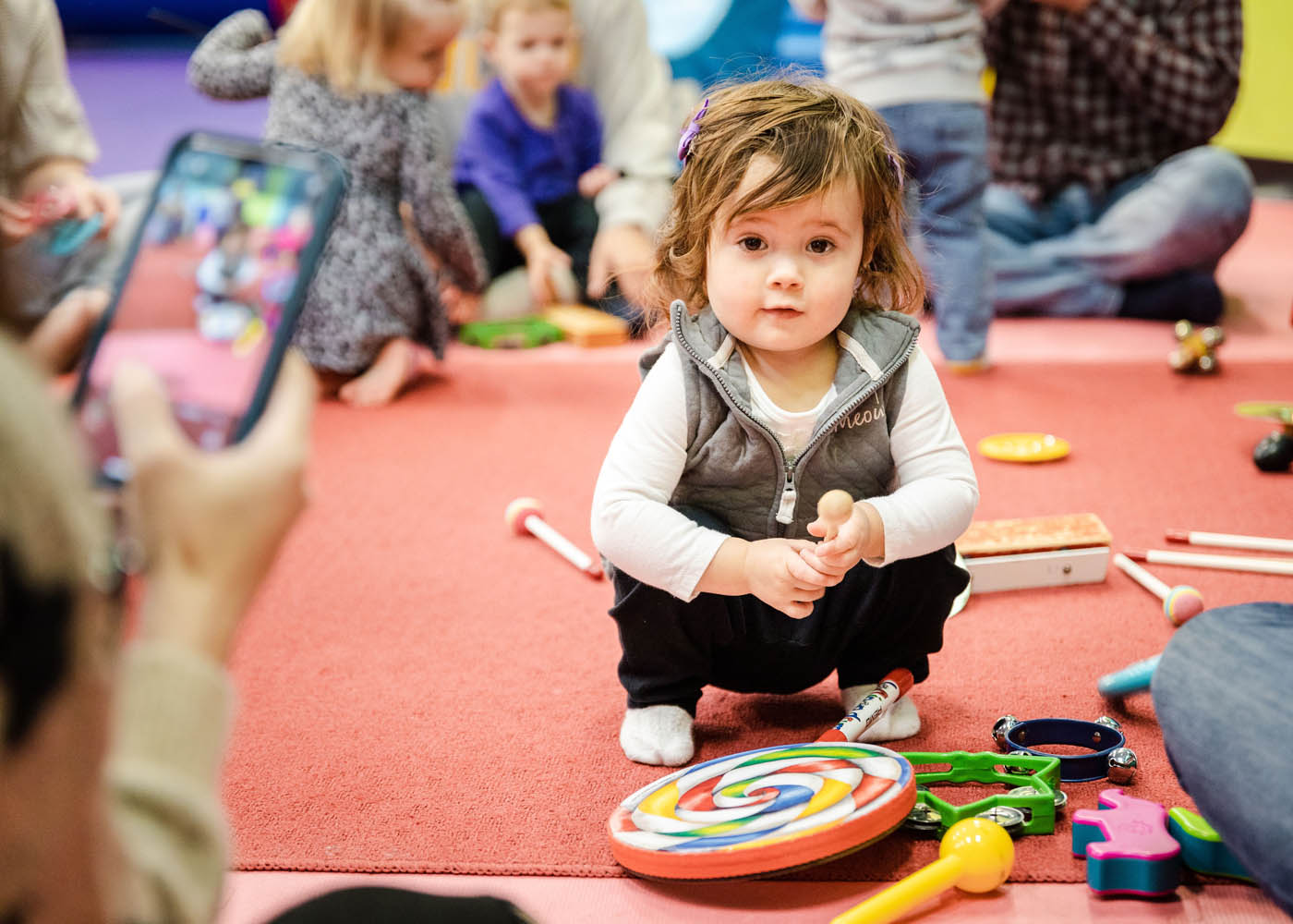 An adorable little girl sitting in front of musical instruments at a Romp n' Roll in Willow Grove baby music class.