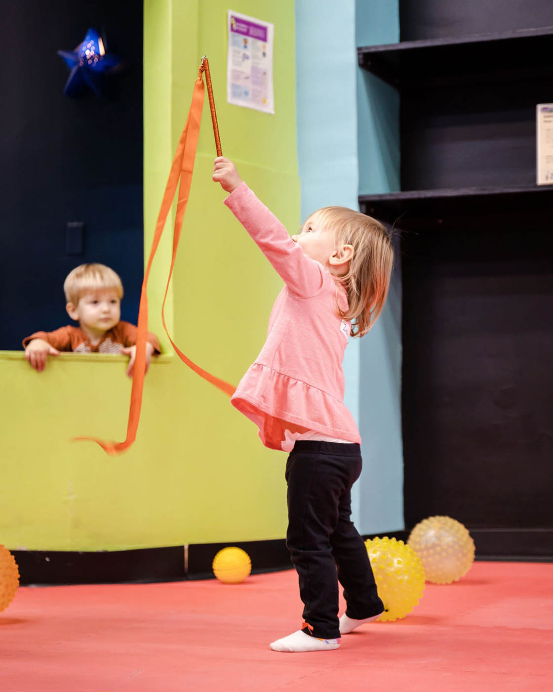 A little girl playing with ribbons and increasing her motor skills in sports classes with Romp n' Roll Willow Grove.