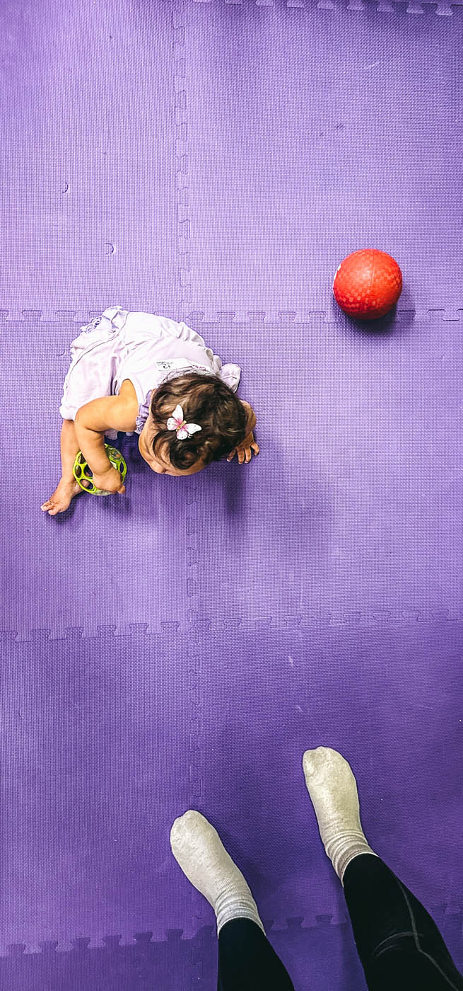 An image of a girl next to a red ball against a purple floor - book with Romp n' Roll Wethersfield today!