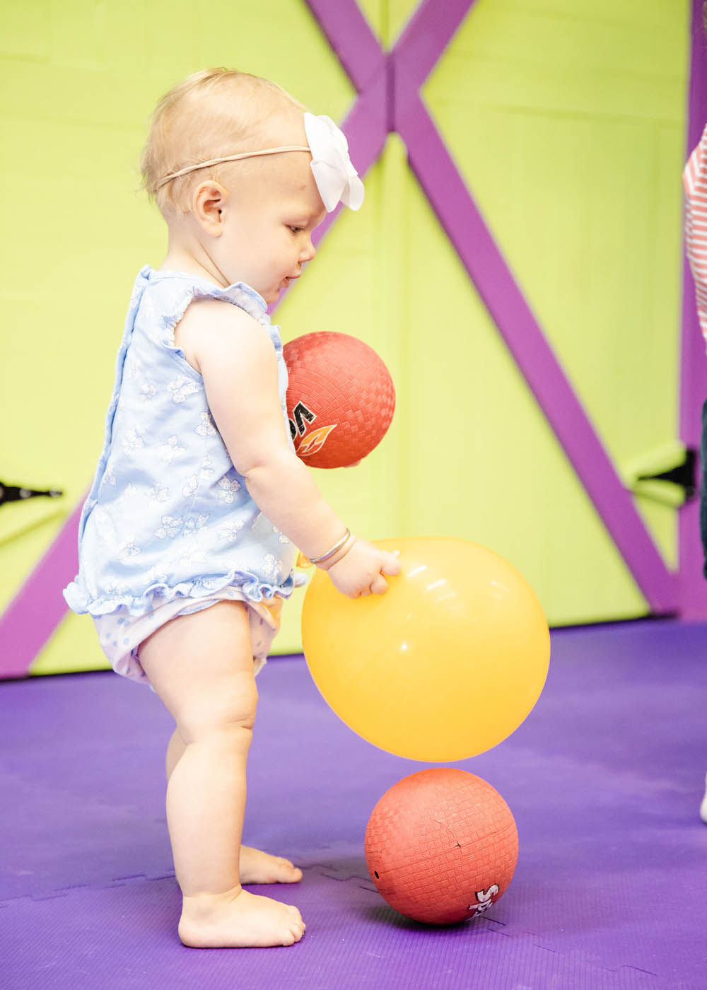 A very little child playing with balls and kid safe equipment in a sports class for 2 year olds in Willow Grove, PA with Romp n' Roll.