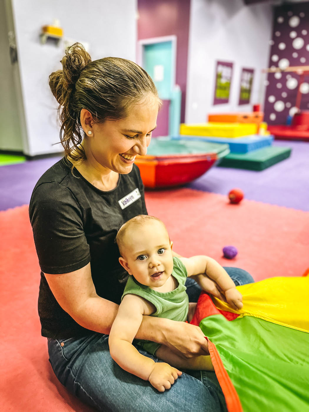 A baby having parachute fun with a Romp n' Roll instructor at our baby activities in Willow Grove, PA.
