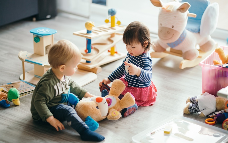 Two toddlers developing social skills by playing together with toys - tips from Romp n' Roll in Raleigh, NC.