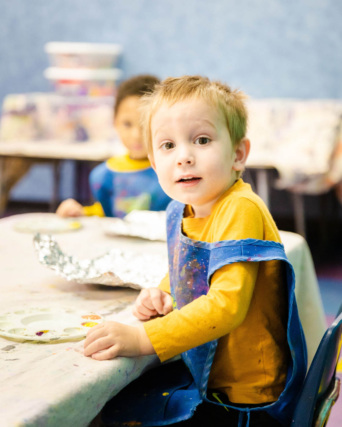 A boy in a yellow shirt in a Willow Grove toddler art class at Romp n' Roll.
