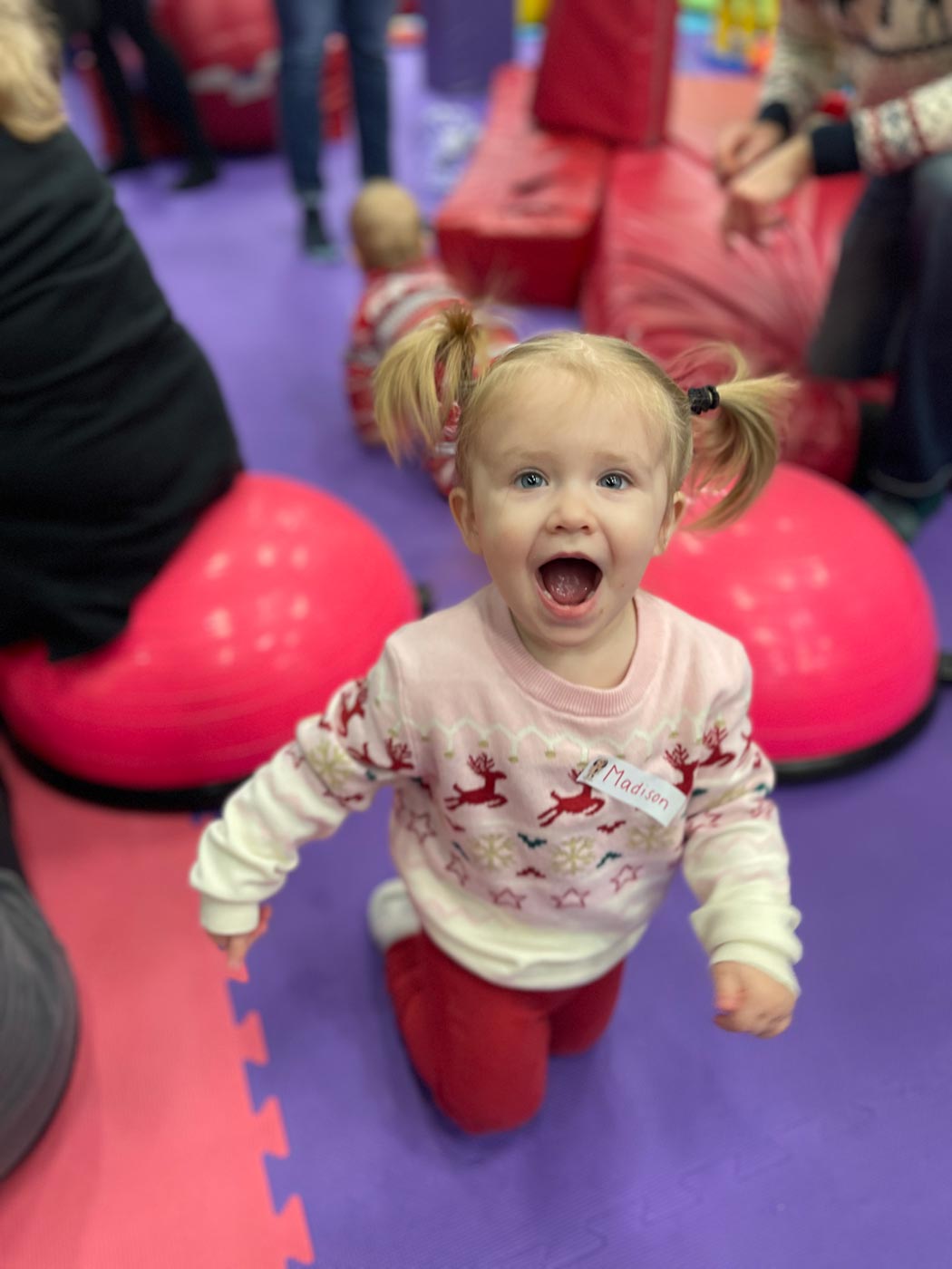 A little girl on a purple matt, having fun at Romp n' Roll's winter camp in Raleigh, NC. 