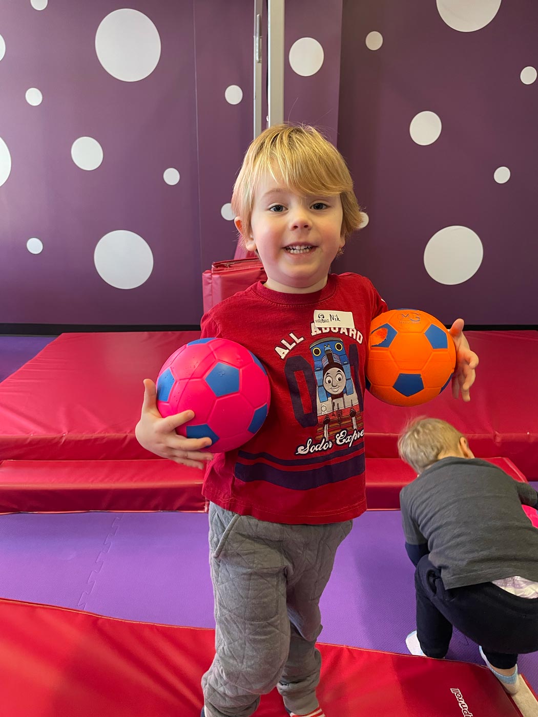 A little boy playing with soccer balls in Romp n' Roll Willow Grove's gym.