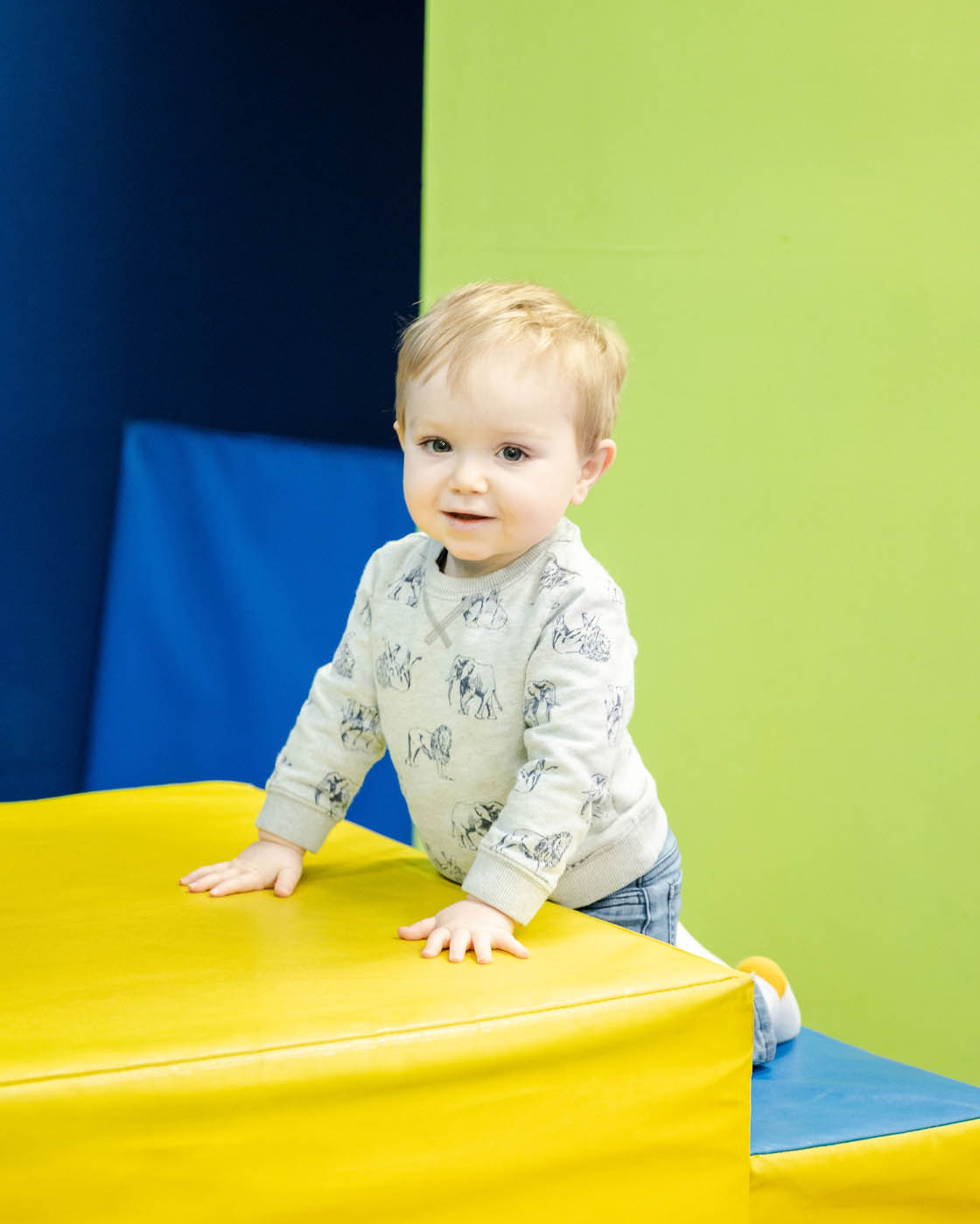 A young boy climbing on some age appropriate gym equipment at a Glen Allen toddler tumbling class.